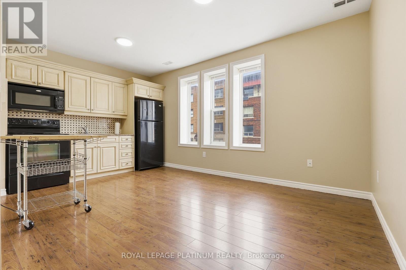 A kitchen with wooden floors and a black refrigerator.