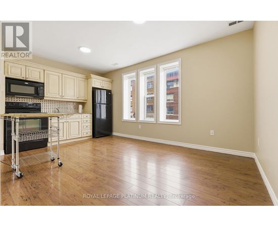 A kitchen with wooden floors and a black refrigerator.