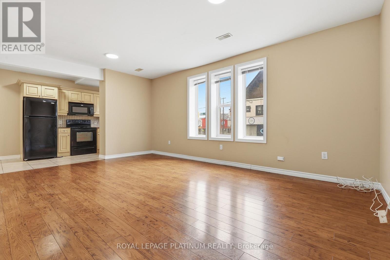 A spacious room with wooden flooring and a large window.