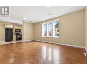 A spacious room with wooden flooring and a large window.