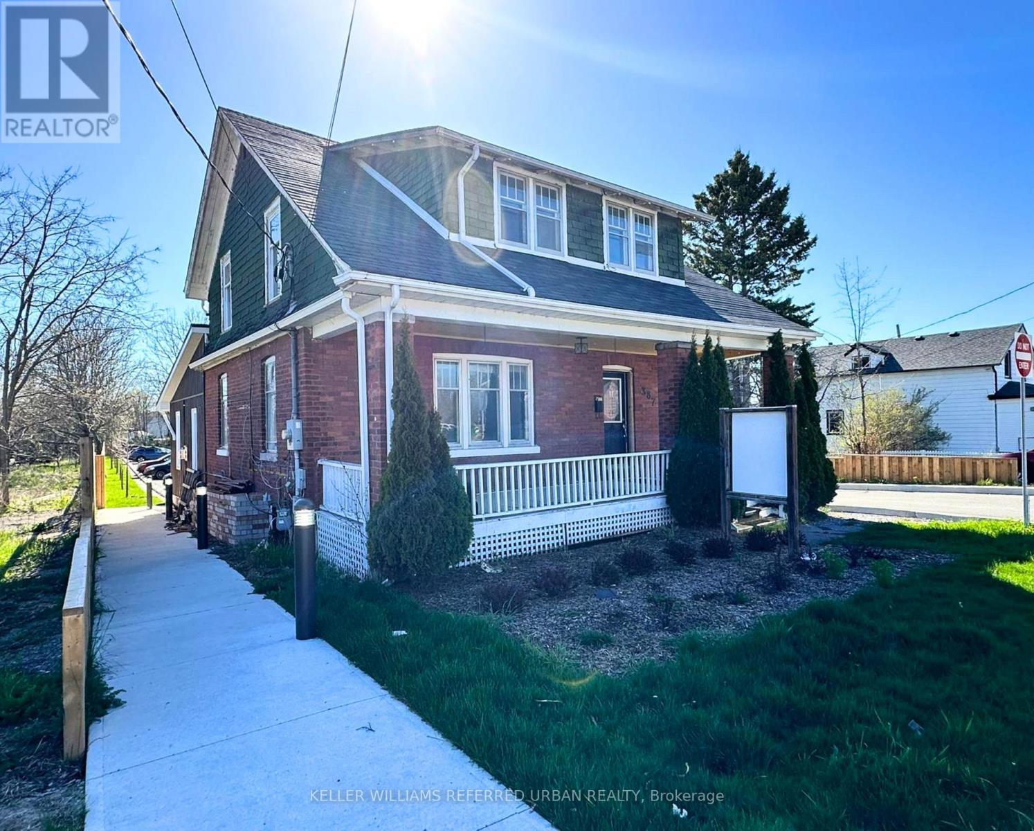 A house with a red brick exterior and a white porch.