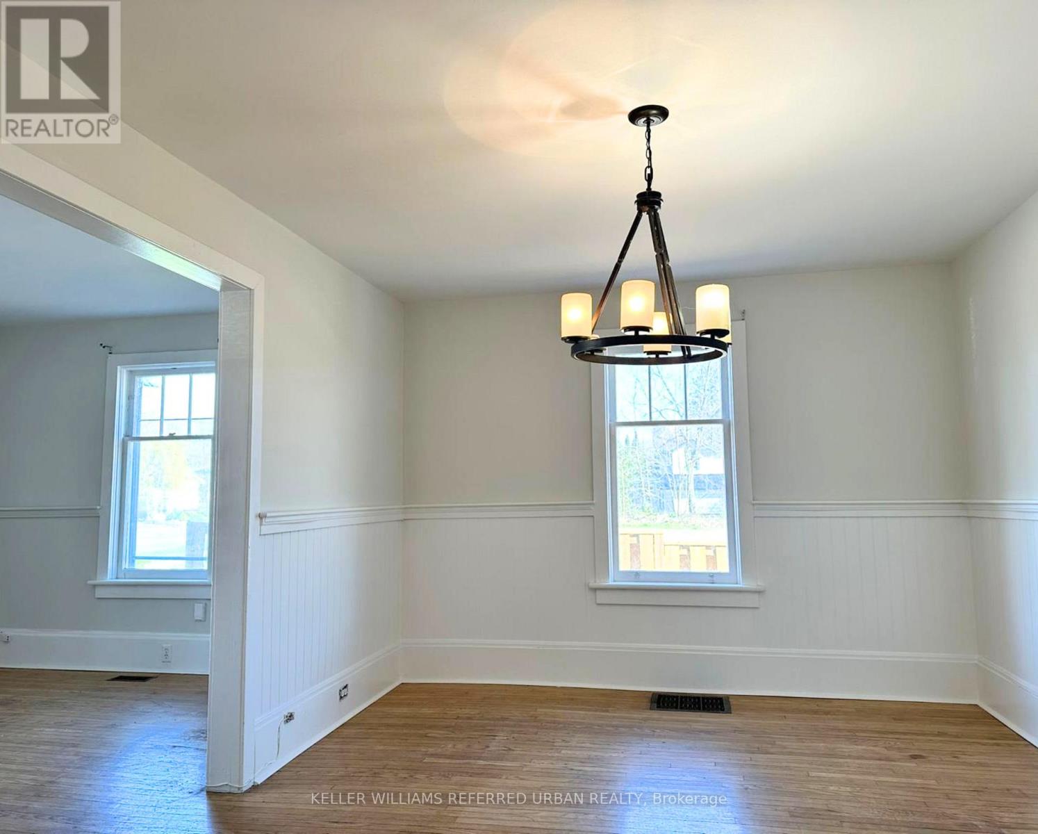 A well-lit room with a chandelier and two windows.