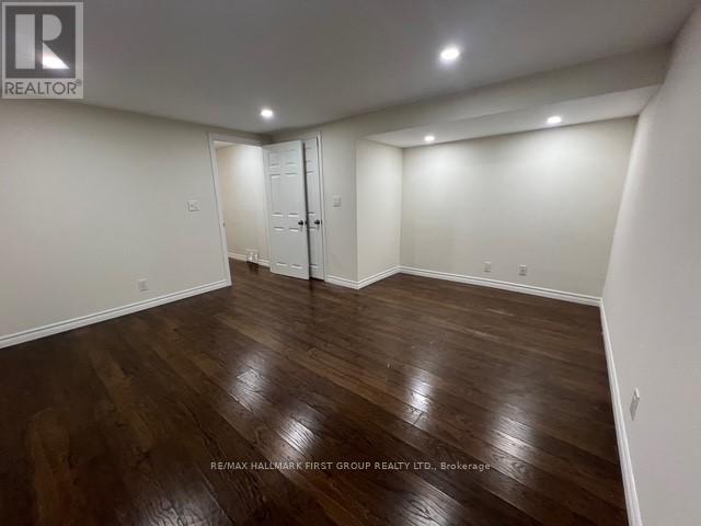 A spacious room with wooden flooring and white walls.
