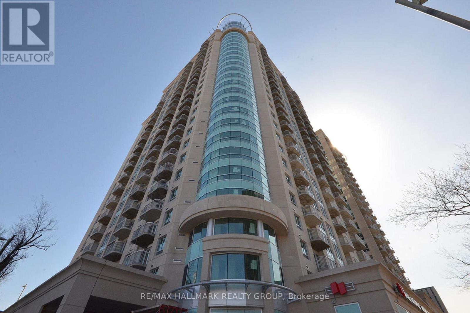 A tall building with a glass facade and a sign that reads "RE/MAX Hallmark Realty Group, Brokerage.".