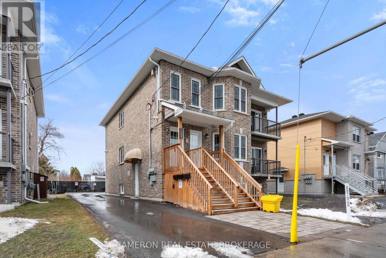 A house with a brown front porch and a yellow post in front of it.