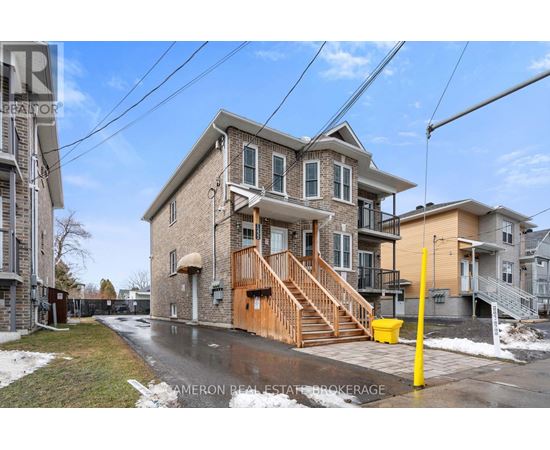 A house with a brown front porch and a yellow post in front of it.