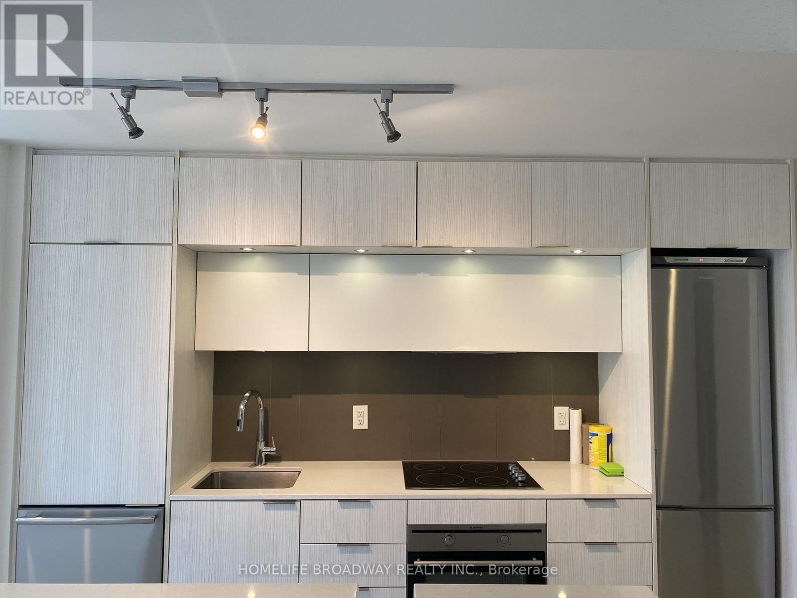 A modern kitchen with white cabinets and stainless steel appliances.