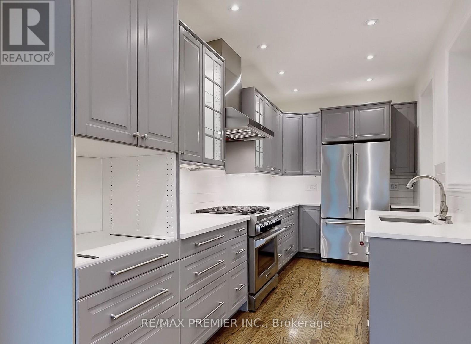 A modern kitchen with stainless steel appliances and wooden floors.