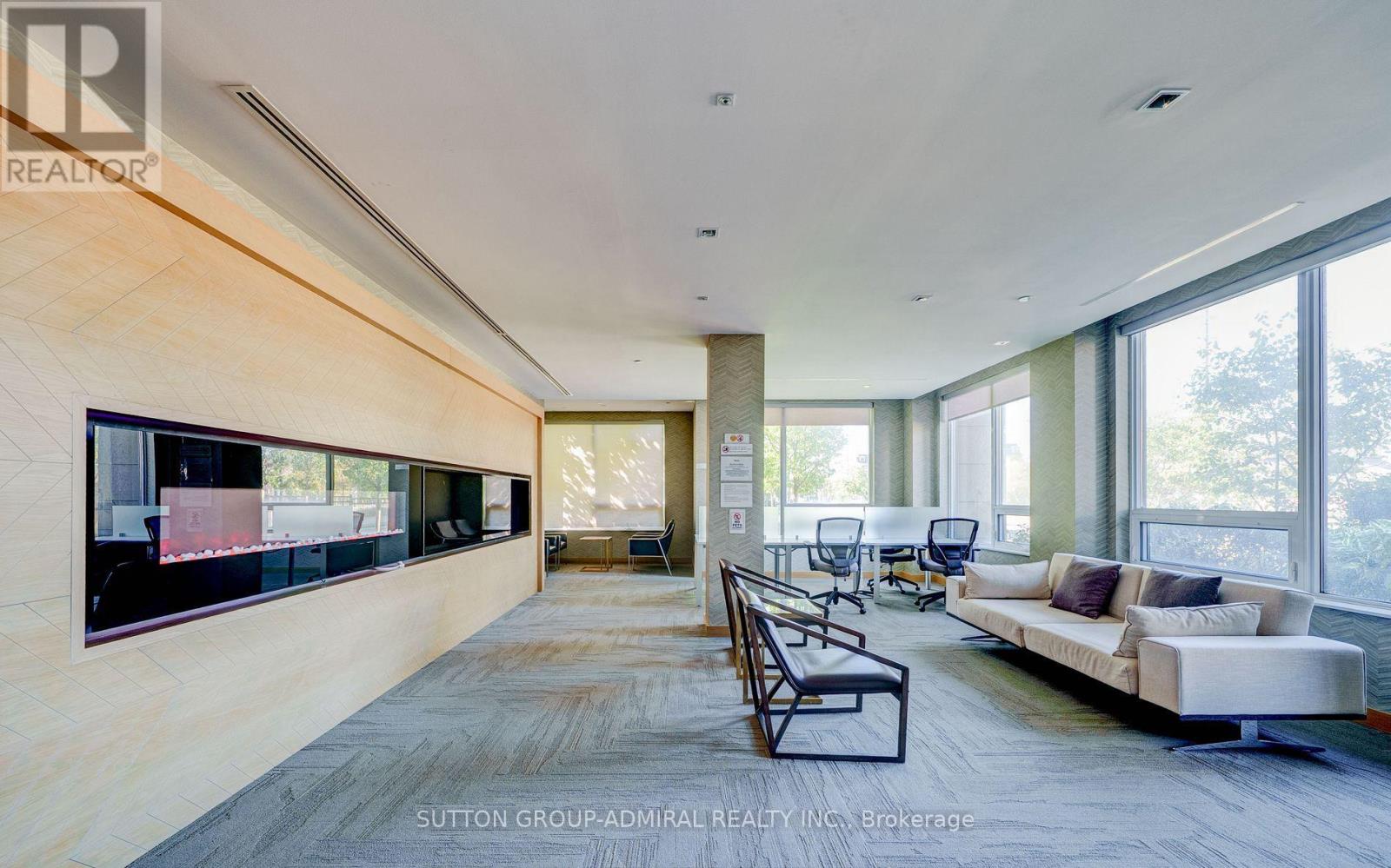 A spacious living room with a long couch and a television on the wall.