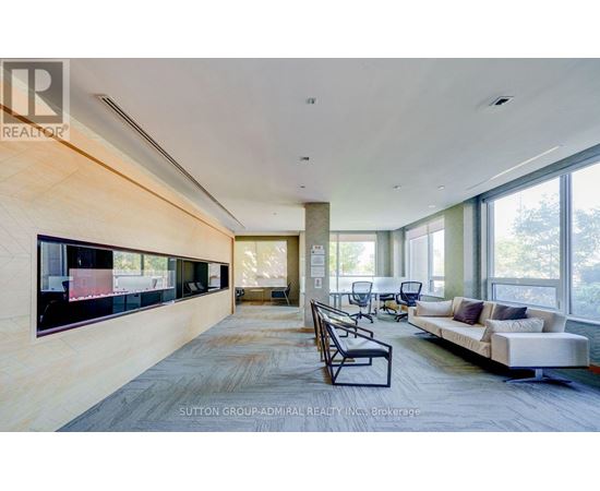 A spacious living room with a long couch and a television on the wall.