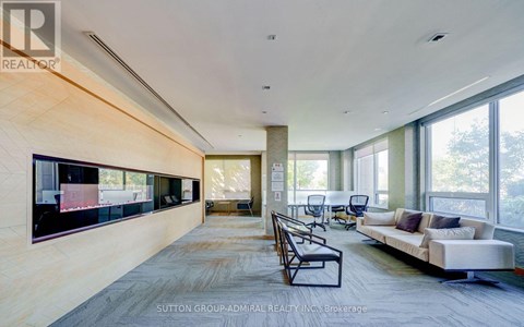 A spacious living room with a long couch and a television on the wall.