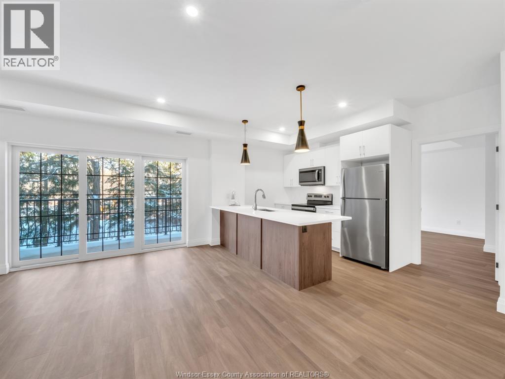 A modern kitchen with wooden floors and stainless steel appliances.