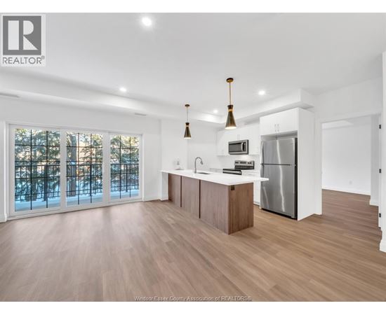 A modern kitchen with wooden floors and stainless steel appliances.