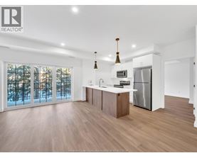A modern kitchen with wooden floors and stainless steel appliances.
