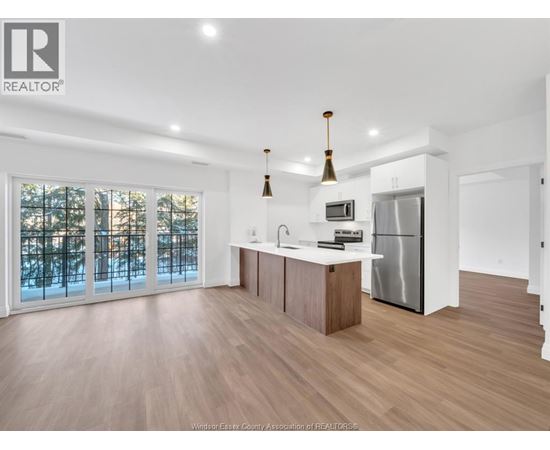 A modern kitchen with wooden floors and stainless steel appliances.