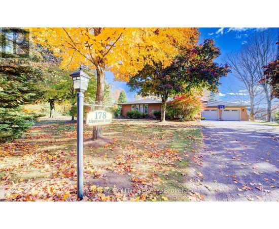 A street sign in front of a house with a tree full of yellow leaves.