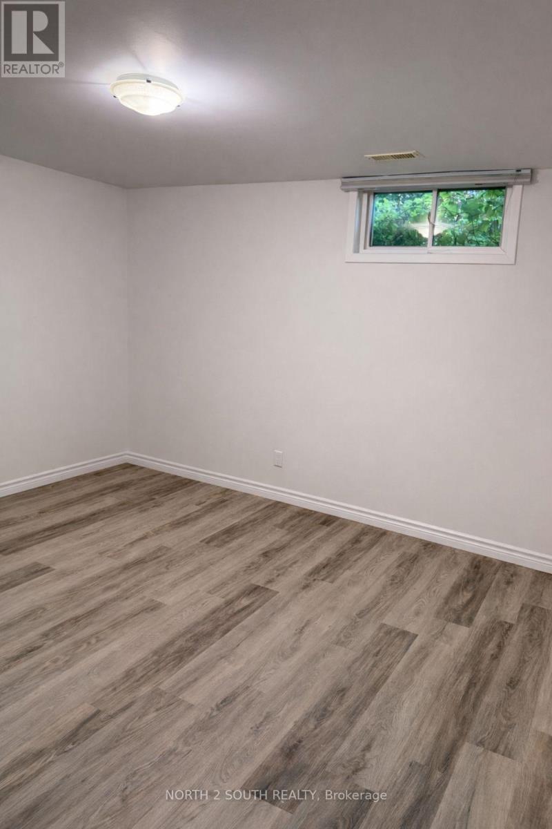 A room with wooden flooring and a window with a view of trees.