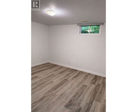 A room with wooden flooring and a window with a view of trees.