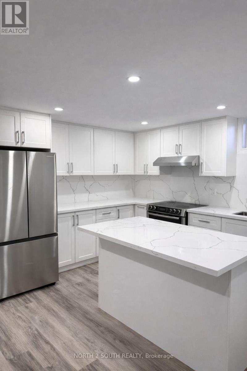 A modern kitchen with white cabinets and a marble countertop.