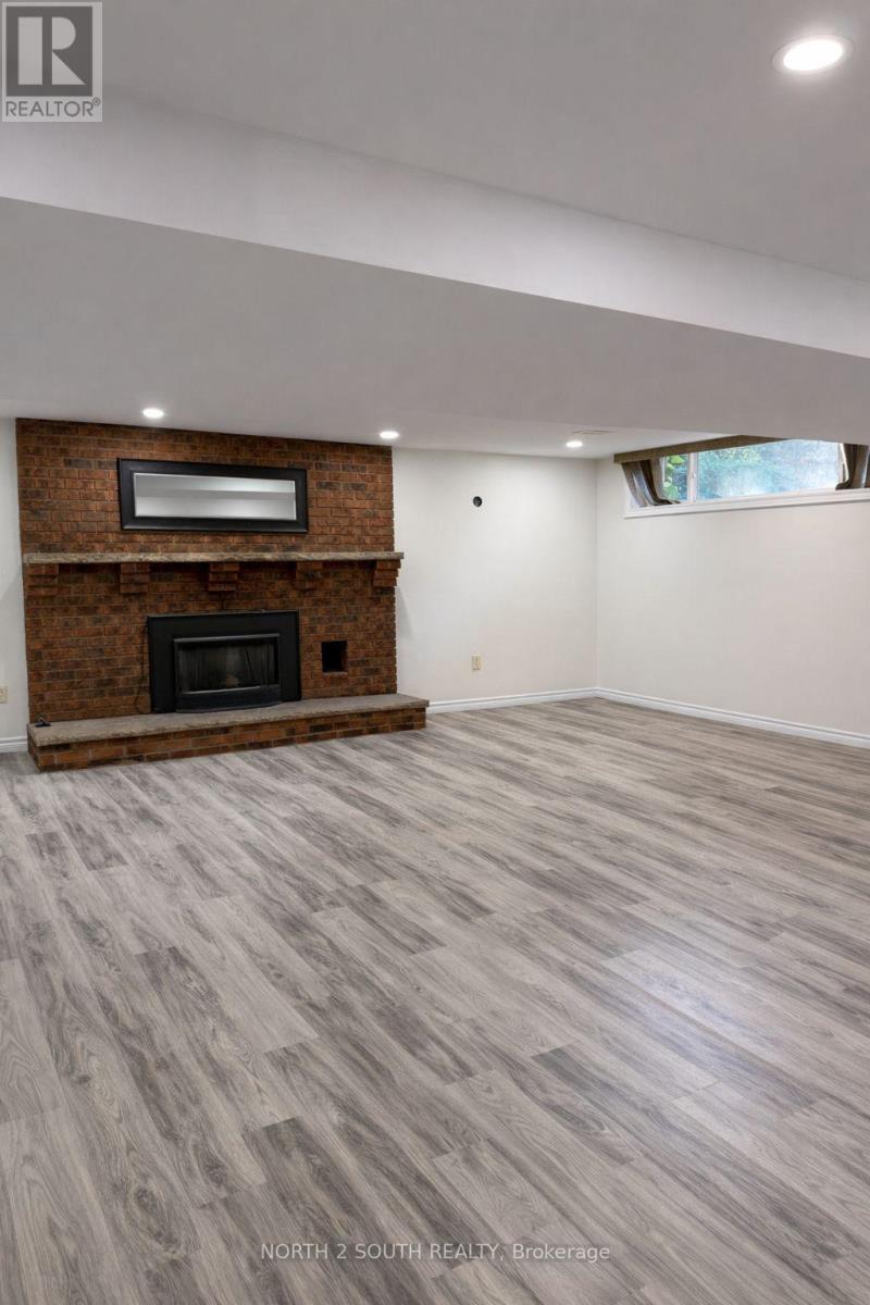 A spacious room with a fireplace and wooden flooring.