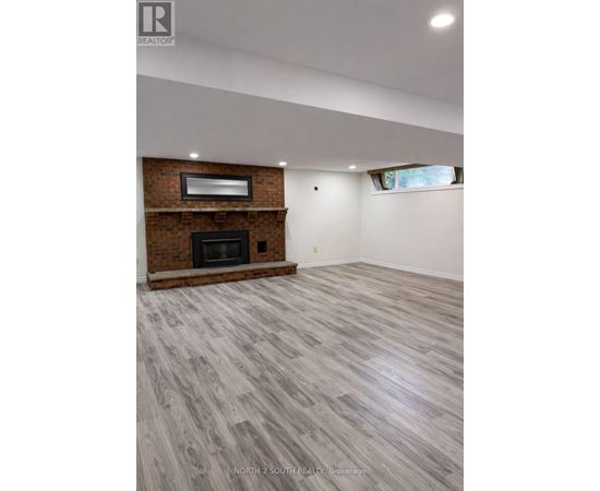 A spacious room with a fireplace and wooden flooring.