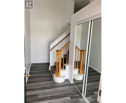 A hallway with a wooden staircase and a glass door.