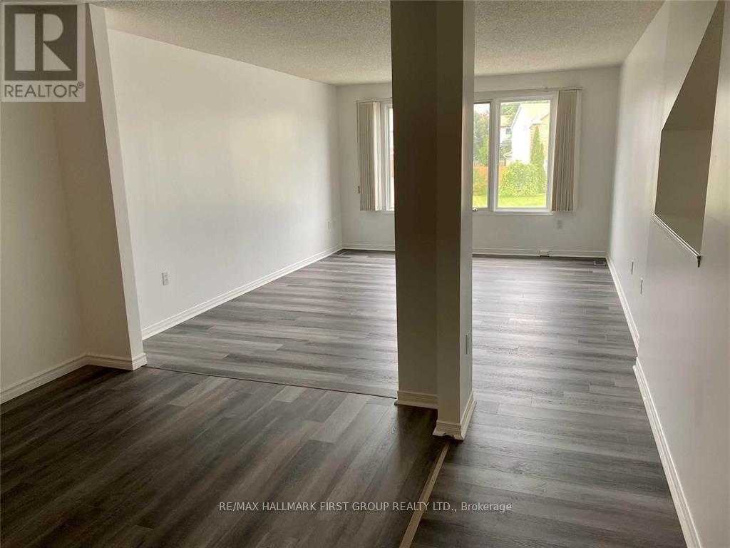 A spacious room with wooden flooring and white walls.