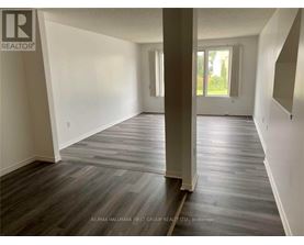 A spacious room with wooden flooring and white walls.