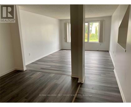 A spacious room with wooden flooring and white walls.