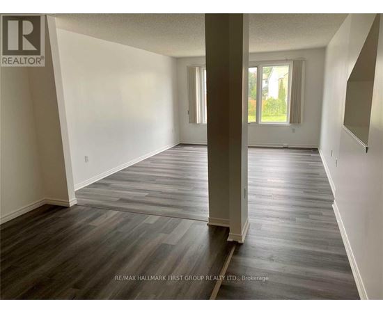 A spacious room with wooden flooring and white walls.