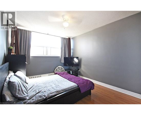 A bedroom with a bed, a fan, and a window.