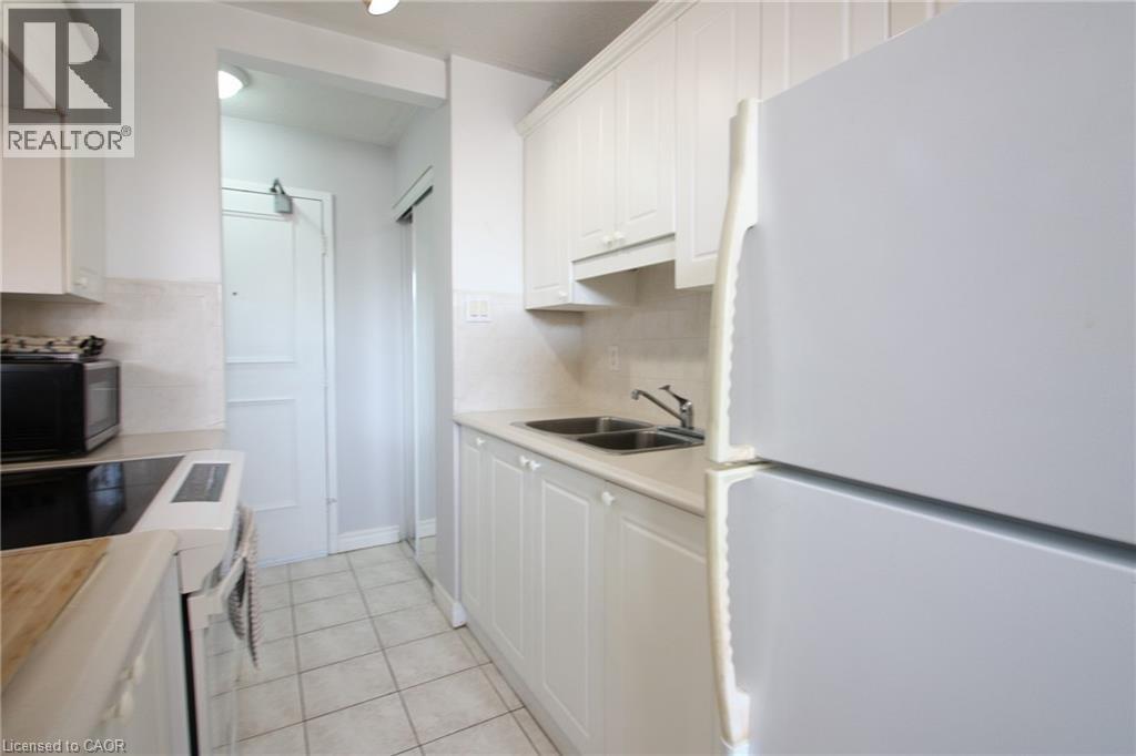 A white kitchen with a refrigerator on the right.