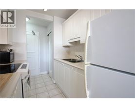 A white kitchen with a refrigerator on the right.
