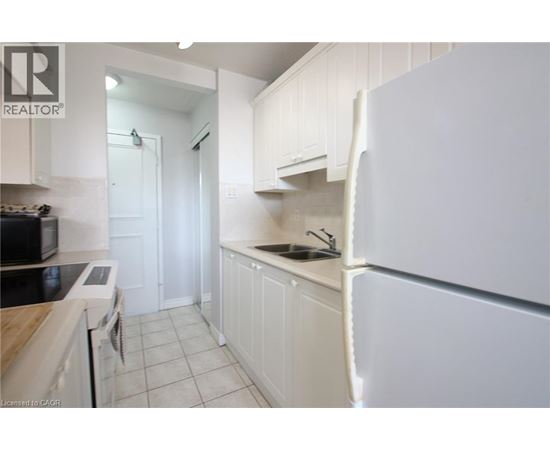A white kitchen with a refrigerator on the right.