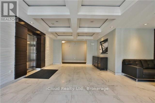 A spacious hallway with a black leather couch and a wooden floor.