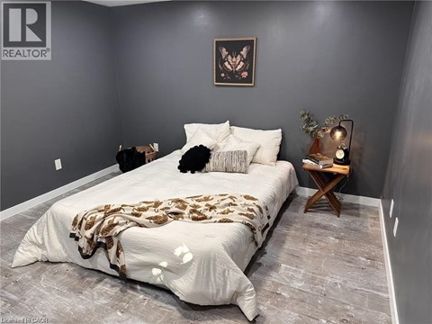A bedroom with a bed covered in a patterned blanket and a small wooden table with a plant on it.