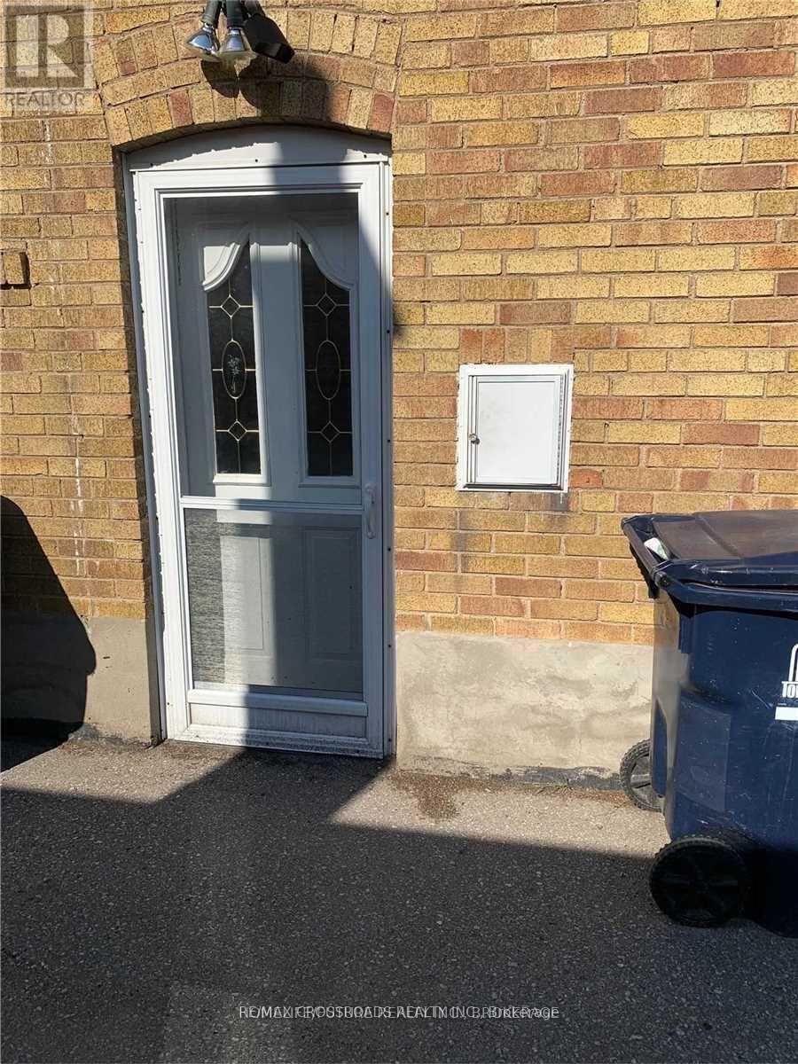 A blue trash bin is placed in front of a white door with a glass window.