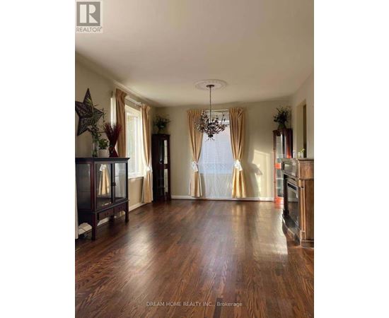 A spacious room with wooden floors and a chandelier.