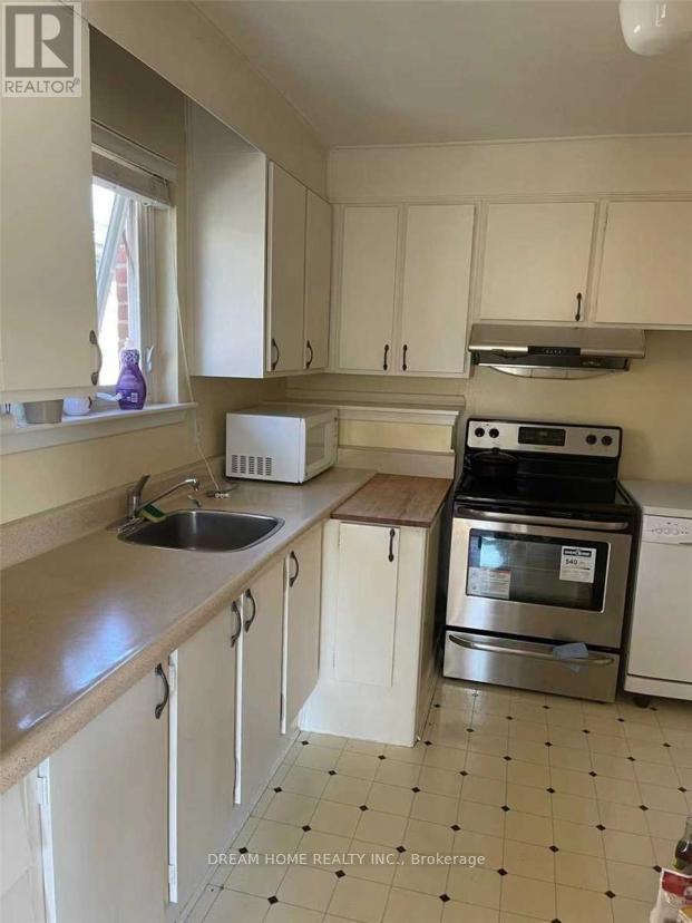 A kitchen with white cabinets and a black and white tiled floor.