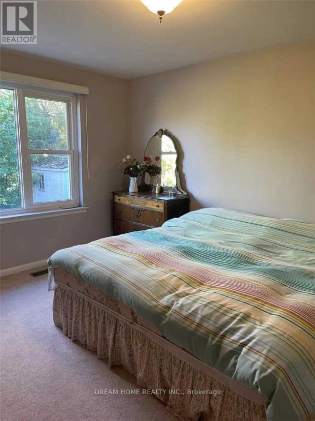 A bedroom with a bed, nightstand, and window.
