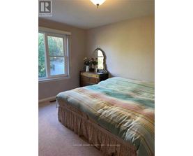 A bedroom with a bed, nightstand, and window.