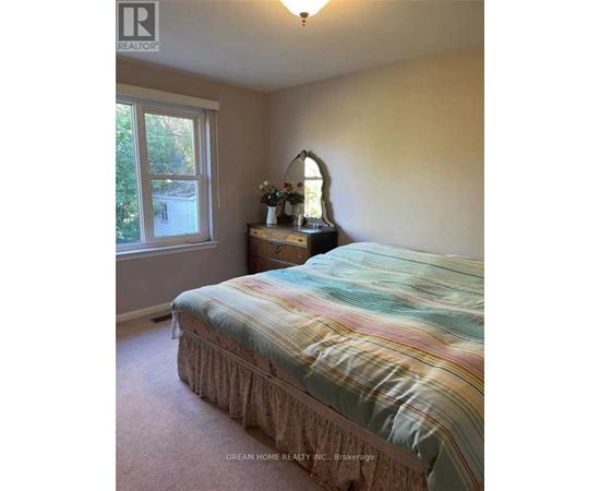A bedroom with a bed, nightstand, and window.