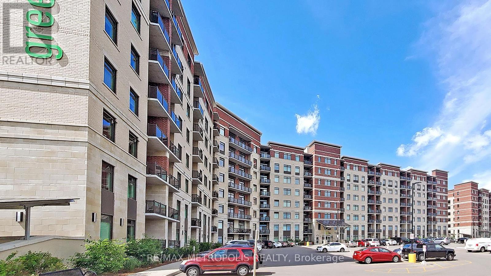 A row of apartment buildings with cars parked in front.
