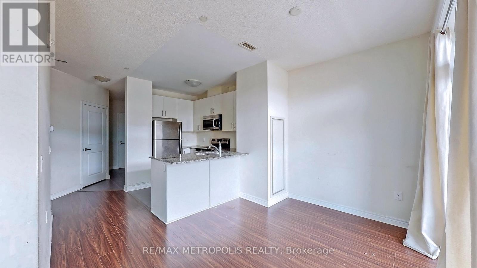 A spacious kitchen with white cabinets and a wooden floor.