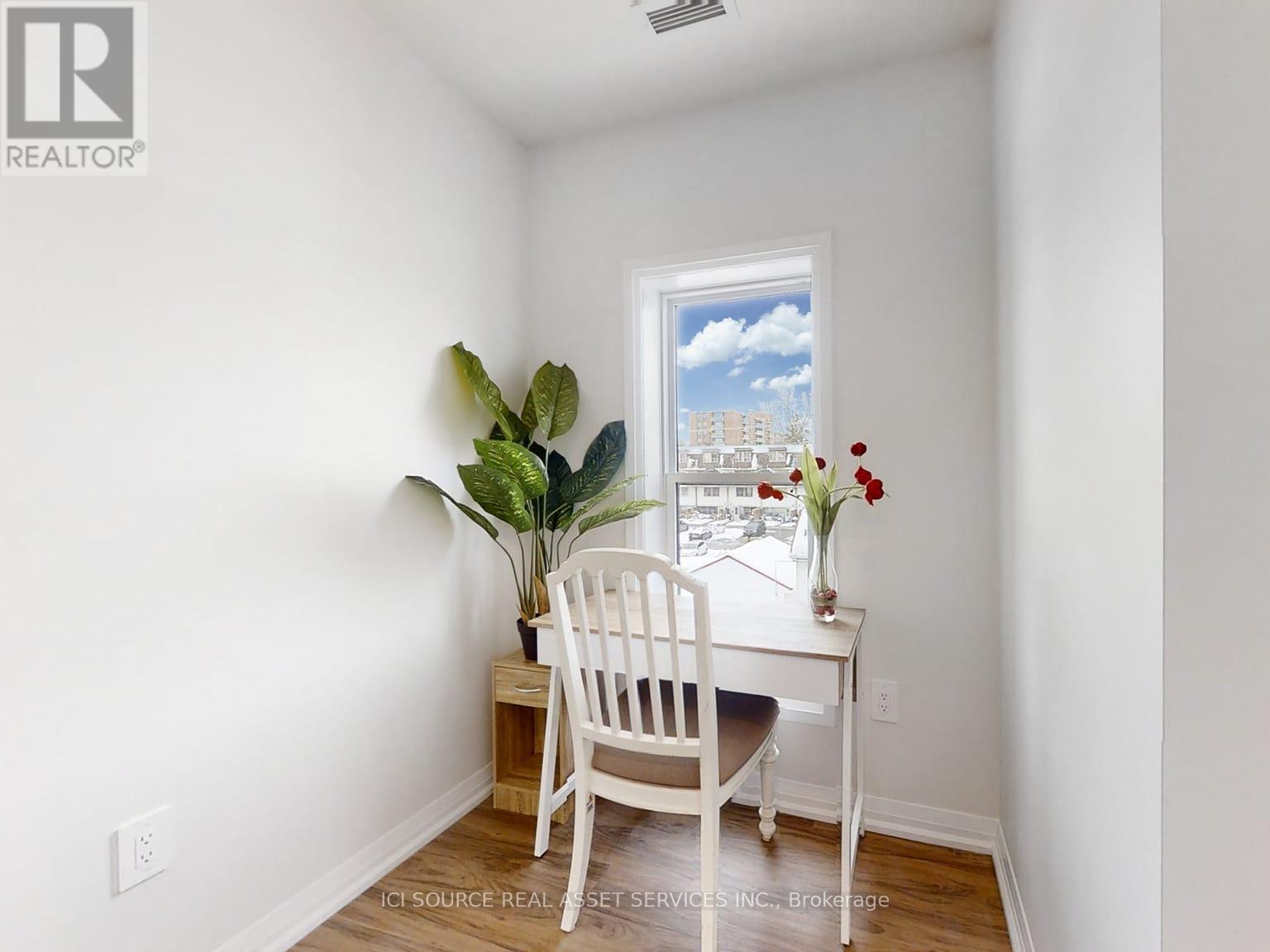 A white chair sits in front of a desk with a plant and a vase of flowers.