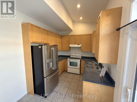 A kitchen with wooden cabinets and a black fridge.
