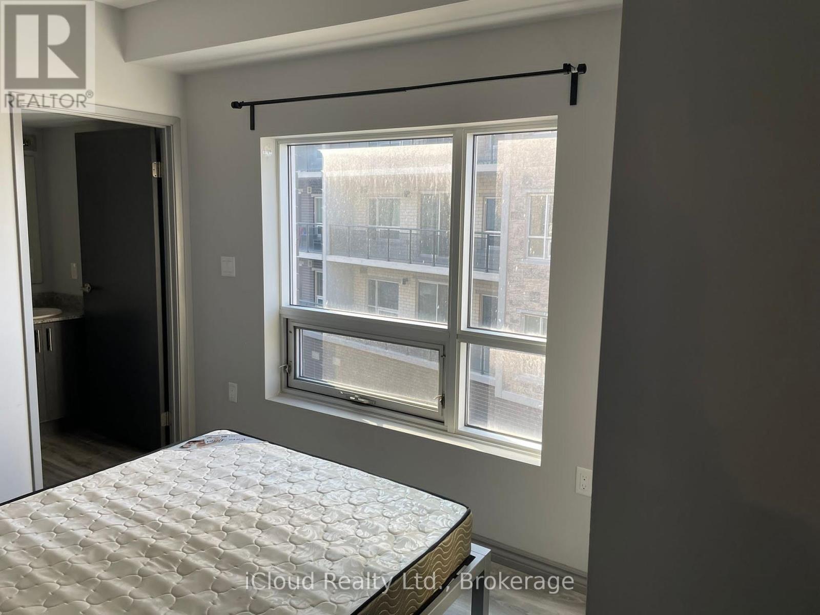 A bedroom with a bed and a window overlooking a building.