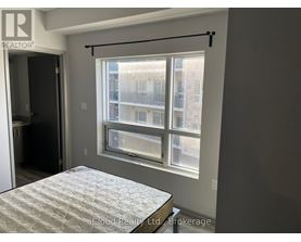 A bedroom with a bed and a window overlooking a building.