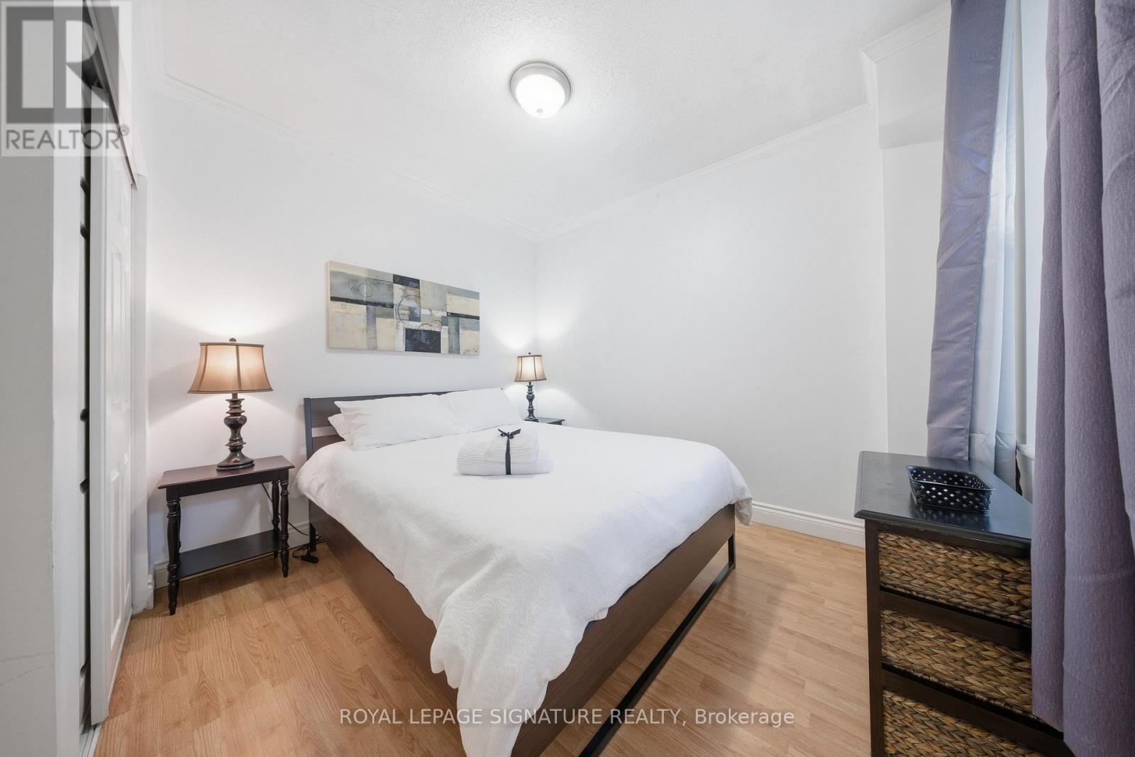 A bedroom with a bed, nightstands, and a painting on the wall.