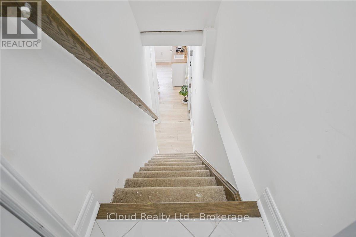 A staircase with a wooden handrail and steps leading to a bright room.